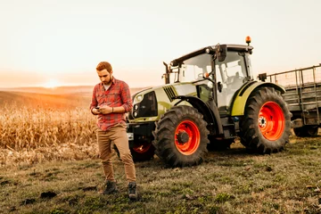 Printed kitchen splashbacks Tractor Farmer working on field using smartphone in modern agriculture - tractor background