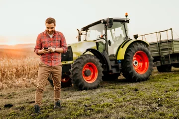 Crédence de cuisine en verre imprimé Tracteur Agriculteur travaillant sur le terrain à l& 39 aide d& 39 un smartphone dans l& 39 agriculture moderne - fond de tracteur