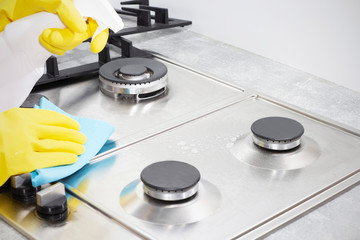 Cleaning a gas stove with kitchen utensils, household concepts, or hygiene and cleaning.