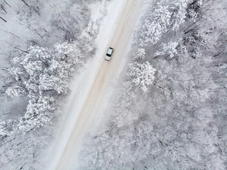 Blick von oben auf ein auto auf einer vereisten Straße im Winter bei Schnee