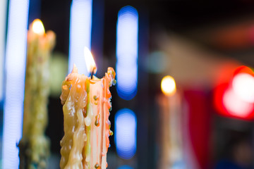 burning candle with streaks on the background of blurry lights