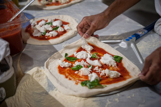Preparing Pizza Margherita on a marble countertops.Pizzaiolo puts pizza dough on the peel. Selective focus   