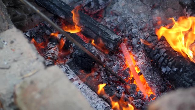 blacksmith works metal. Craftsman, the Highlander on private smithy in the village. Burning logs in the blacksmith's furnace. Removing the preform from scorching hot crucible, using the poker. Slow