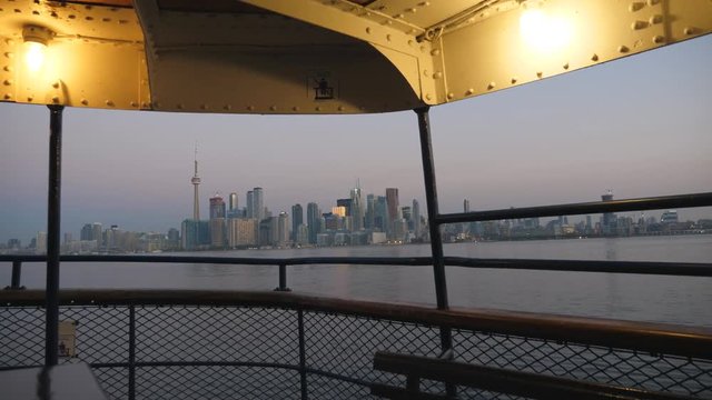 Dawn view of Toronto skyline as ferry Sam McBride pulls into Ward's island. Summer. Seagulls fly by.