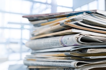 Pile of printed newspapers on white background