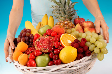WOMAN HOLDING BASKET OF FRESH FRUIT