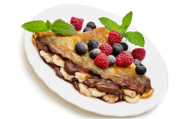 Homemade crepes served with chocolate cream, fresh blueberries and raspberries, powdered sugar on a white background