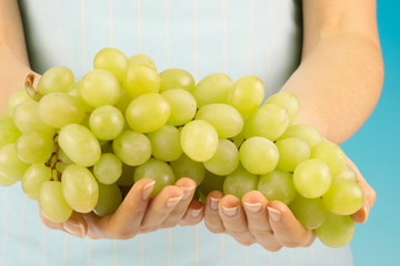 WOMAN WITH HANDFUL OF GREEN GRAPES