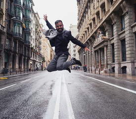 Un chico joven feliz salta en el medio de la calle Via Laietana de Barcelona en un día lluvioso