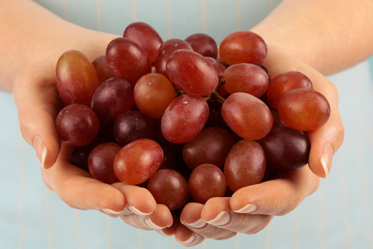 WOMAN WITH HANDFUL OF RED GRAPES