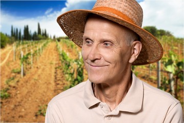 Happy senior man in hat at work on field