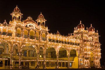Mysore Palace front facade lighted up with multiple bulbs at night. Historical royal building in Karnataka, India. Guided tour, visit destination concepts