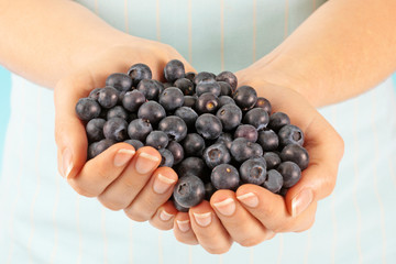 WOMAN WITH HANDFUL OF FRESH BLUEBERRIES