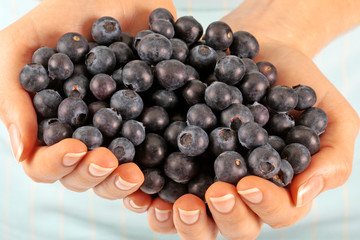 WOMAN WITH HANDFUL OF FRESH BLUEBERRIES