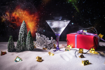 Winter Cocktail - Alcoholic drink and snow scene with a Christmas theme or Ideas and recipes for Christmas drink. Glass of martini on snow with Christmas decoration