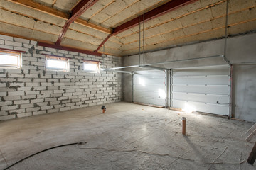 Large garage for two cars with of the gate. overhaul and reconstruction. Working process of warming inside part of roof. House or apartment is under construction, remodeling, renovation, restoration.