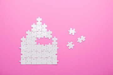 White puzzle. House shape puzzle. The concept of rent, mortgage. Pink background. Top view