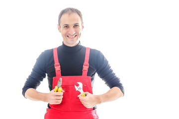 Young mechanic in uniform with crossed arms and wrenches standing, isolated on white