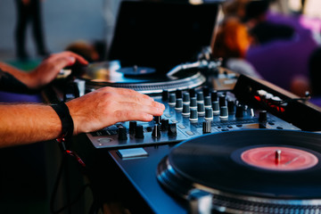 Dj hands on a mixer and turntables with the vinyl