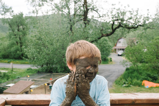Boy puts mud on his face