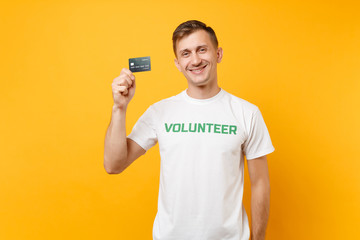 Portrait of man in white t-shirt with written inscription green title volunteer hold in hand credit...