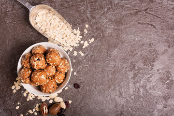 Healthy organic energy granola bolls with nuts, cacao, oats and raisins - vegetarian sweet bites without sugar. Dark background, top view