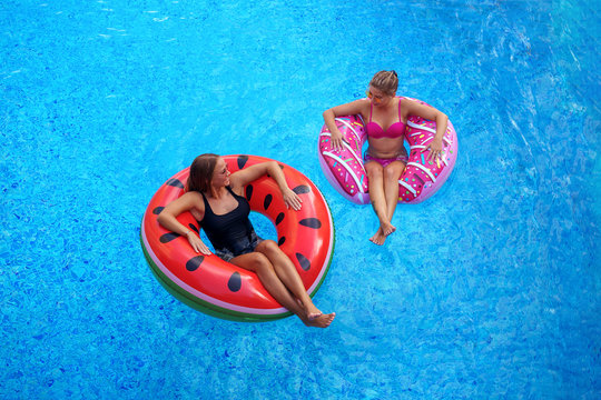 happy girls in bikini smiling and smimming in pool on inflatable watermelon mattresses