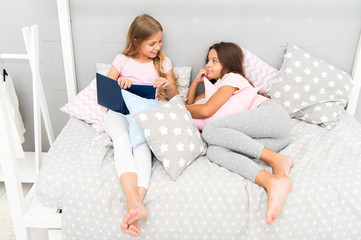 Obraz na płótnie Canvas Kids prepare go to bed. Pleasant time cozy bedroom. Girls long hair cute pajamas relax read book. Satisfied with book happy end. Their favorite book. Girls sisters lay bed read book together