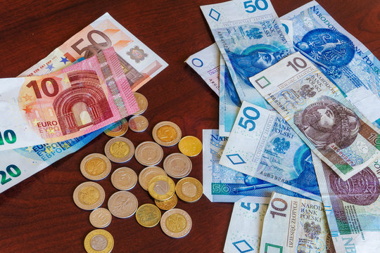 Polish zloty - zl money banknotes and coins with euro banknotes. Official currency of Poland in denominations of 10, 20 & 50 zloty bills with groszy coins on table next to 10, 20 & 50 euro bills.