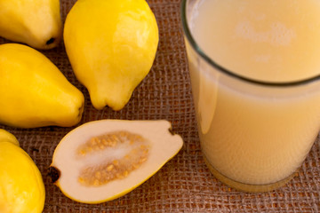 Fresh guava smoothie or juice in glass, ripe guava fruit and cut half on sackcloth background.