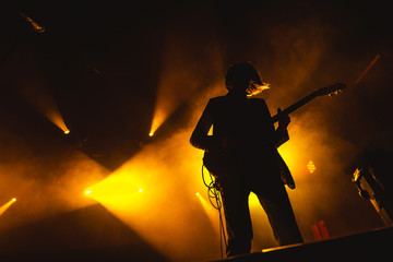 Naklejka premium Gitarzysta gra solo. sylwetka gitarzysty w akcji na scenie muzycznej. na scenie występuje popularny zespół rockowy.