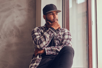 Naklejka premium Pensive African-American bearded man looking out the window.