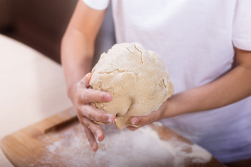Children's hands knead the dough on a wooden cutting board. close-up. dough recipe, cooking technology