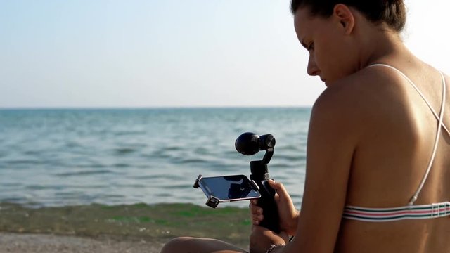 Attractive female records video with modern 3d gimbal stabilized camera osmo and smartphone