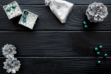 Silver Christmas decorative accessories, pine cones, white and emerald green beads. Space for text.