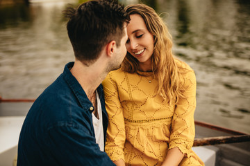 Close up of a couple in love sitting together near a lake