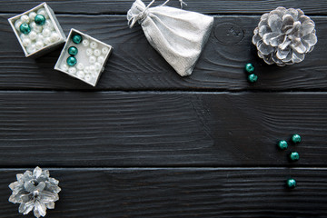 Silver Christmas decorative accessories, pine cones, white and emerald green beads. Space for text.