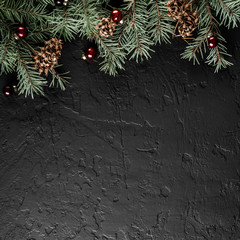 Christmas Fir branches with pine cones on dark black background. Xmas and Happy New Year card, bokeh, sparking, glowing. Flat lay, top view