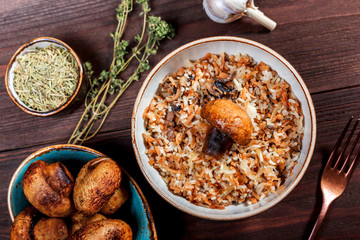 Fried noodles with rice and baked mushrooms on plate on wooden background. Healthy food. Top view