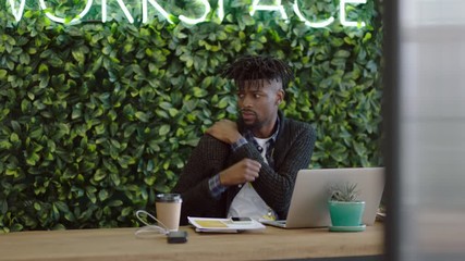 bored businessman at work young african american man looking unmotivated expressing boredom lazy employee tired stretching arms in workplace