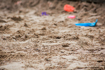 Fototapeta na wymiar Sand with blurry plastic toys in the distance