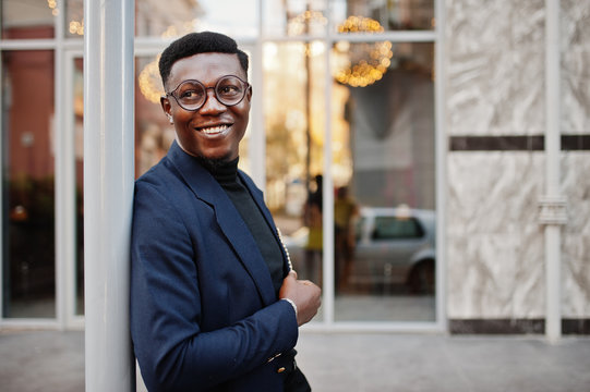 Amazingly looking african american man wear at blue blazer with brooch, black turtleneck and glasses posed at street. Fashionable black guy.