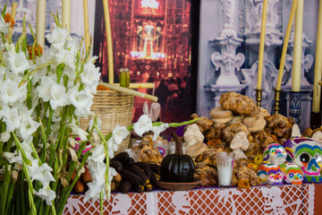 A typical scene of an altar during the day of the dead celebration in mexico with skull candy, handmade baskets, colorful decoration, flowers and candles .