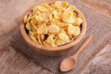 Crunchy corn flakes in wooden bowl with burlap napkin