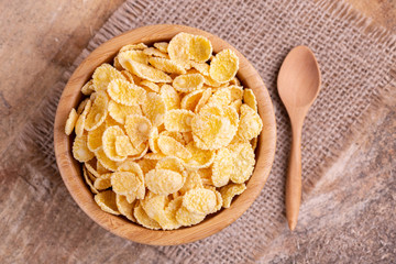 Crunchy corn flakes in wooden bowl with burlap napkin