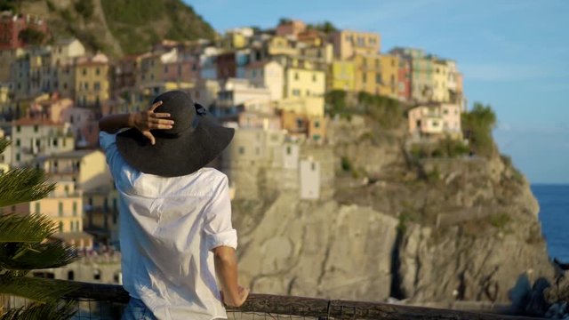 girl in a hat looks at the city of Manarola Italy