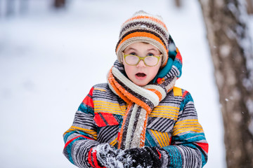 Smiling boy with green big glasses, knitting hat and scarf. Winter snowy background