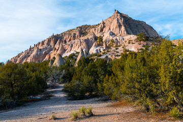Naklejka premium Kolorowy czerwony szczyt skalny z licznymi formacjami skalnymi hoodoo w wieczornym świetle przy pomniku narodowym Kasha-Katuwe Tent Rocks w pobliżu Santa Fe w Nowym Meksyku