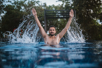 A young guy swims in the outdoor pool. Man splashing water