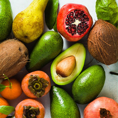 different fruits of pomegranate, pear, mandarin, lemon, avocado and persimmon with coconut on the table. basis of healthy nutrition and daily juices